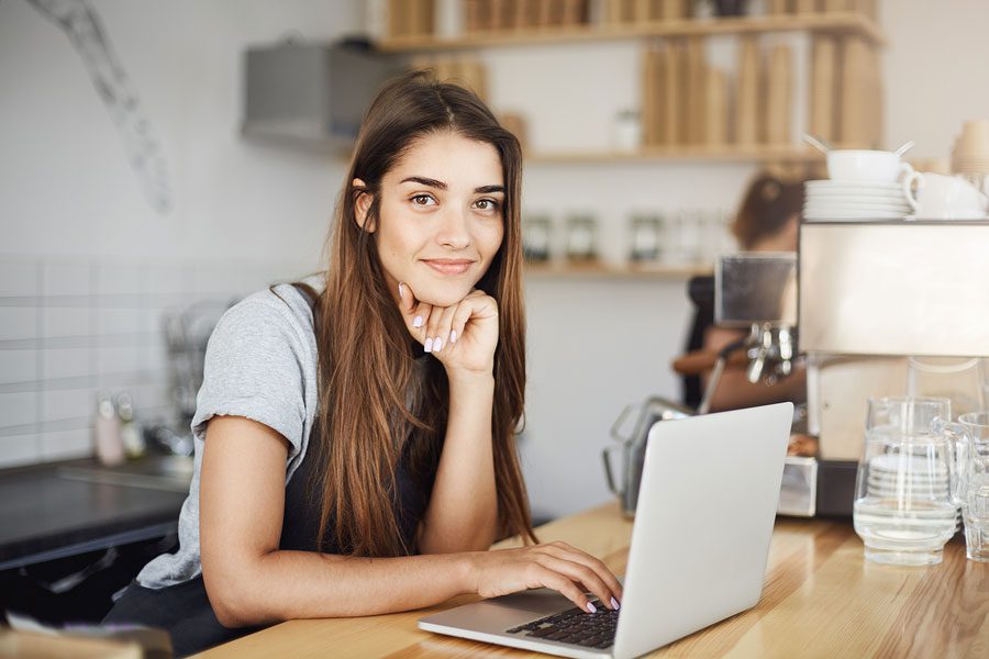 A woman sitting at a table with her laptop.