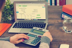 A person using a calculator on top of a desk.