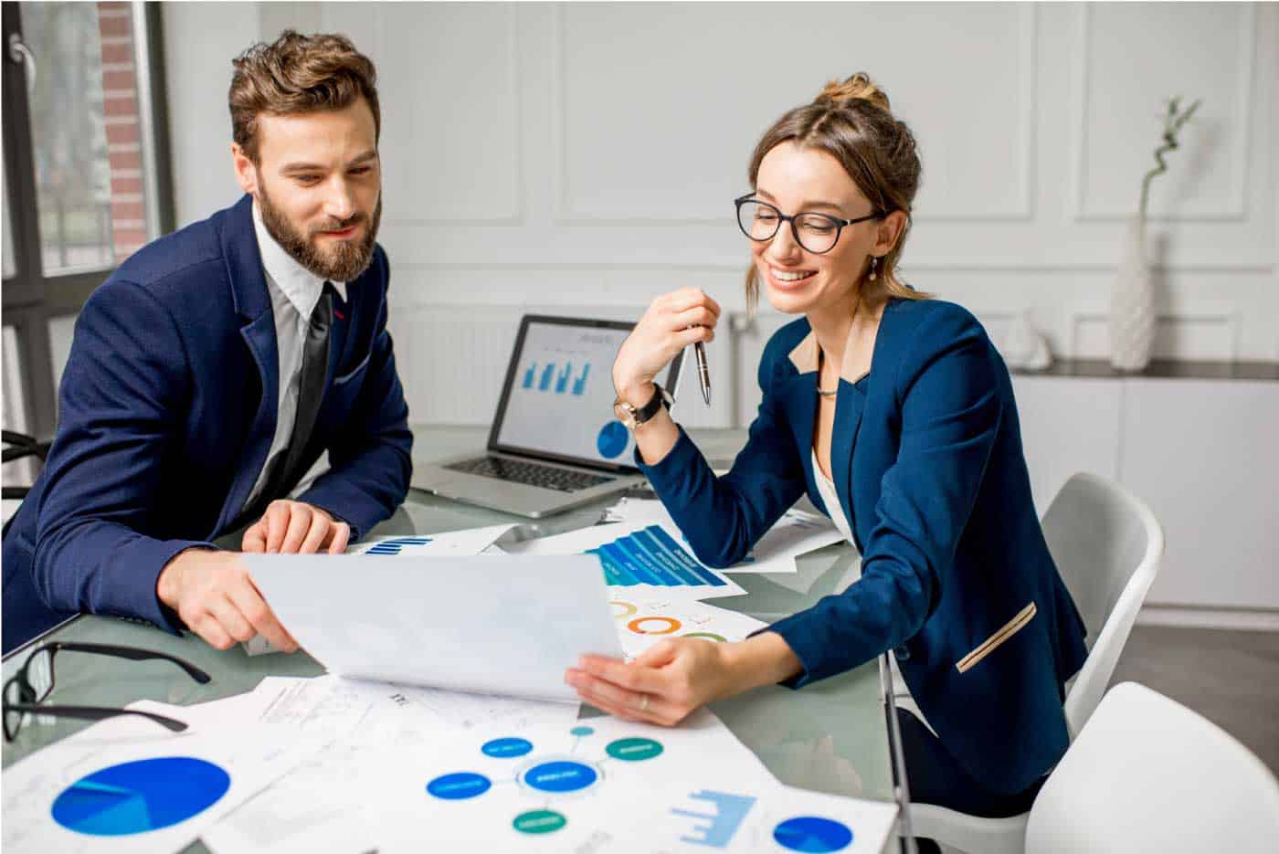 Two people sitting at a table looking at papers.