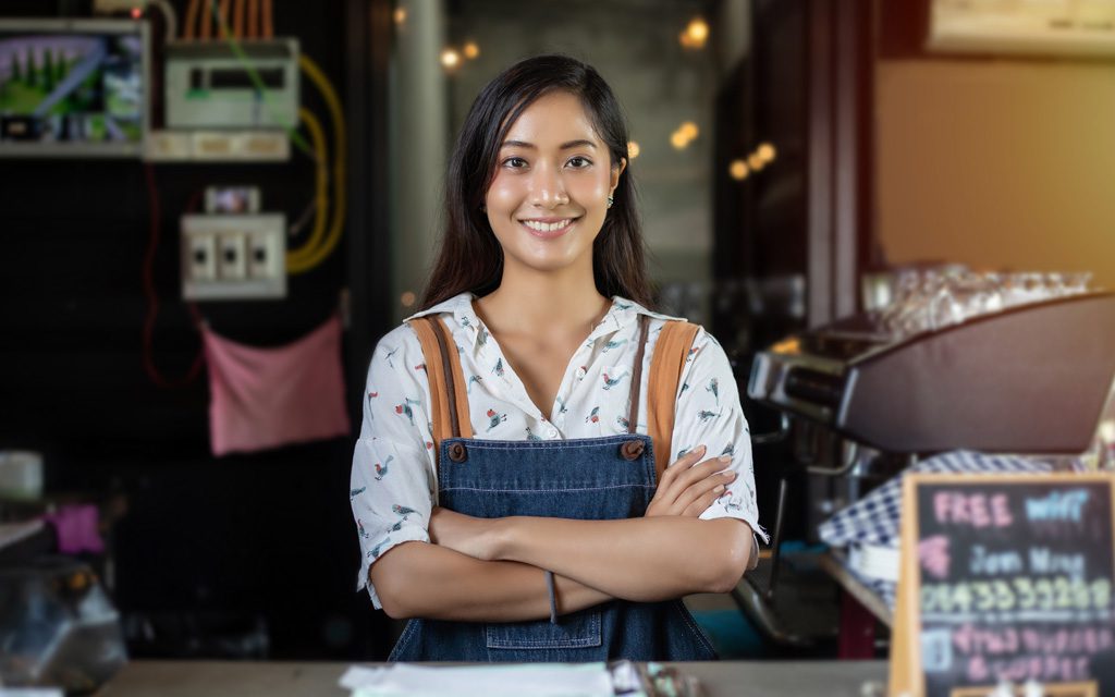 A woman standing in front of a counter with her arms crossed.