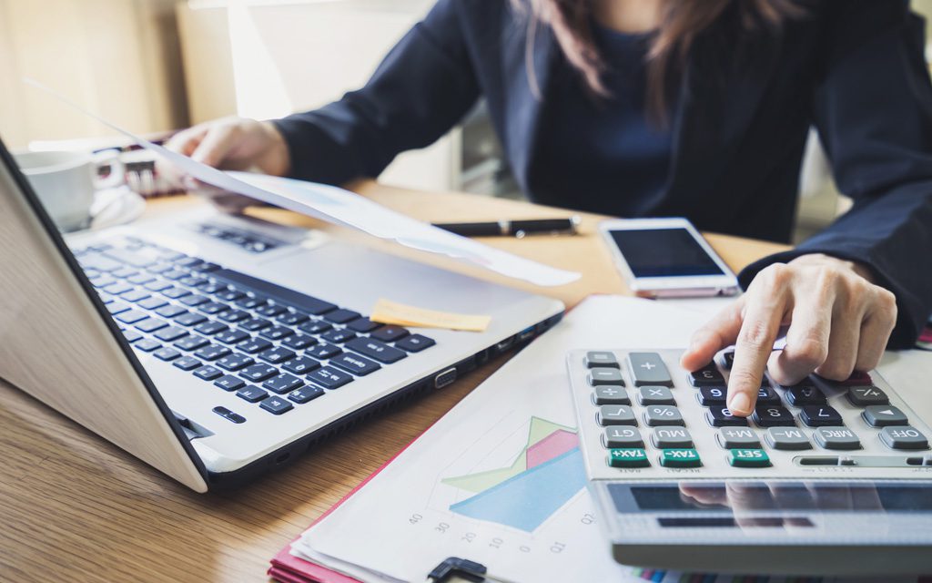 A person sitting at a table with some papers and a calculator