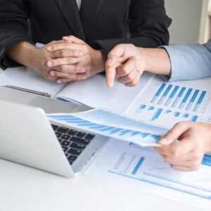 Two people sitting at a table with papers and a laptop