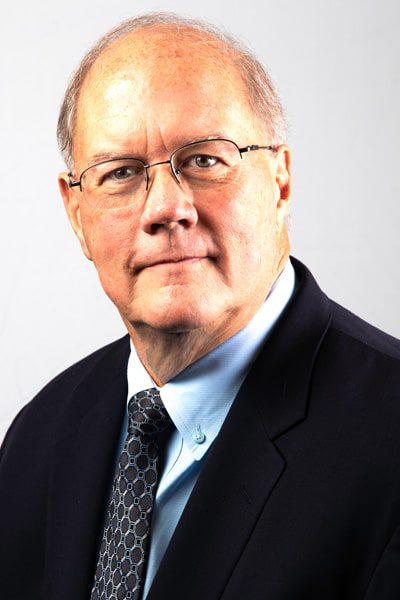 A man in glasses and suit jacket with white background