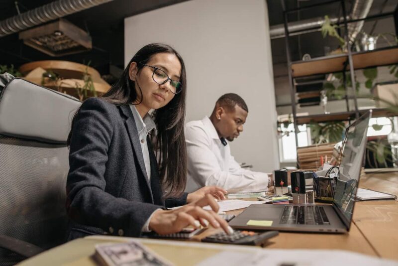 A woman and man sitting at a table with laptops.